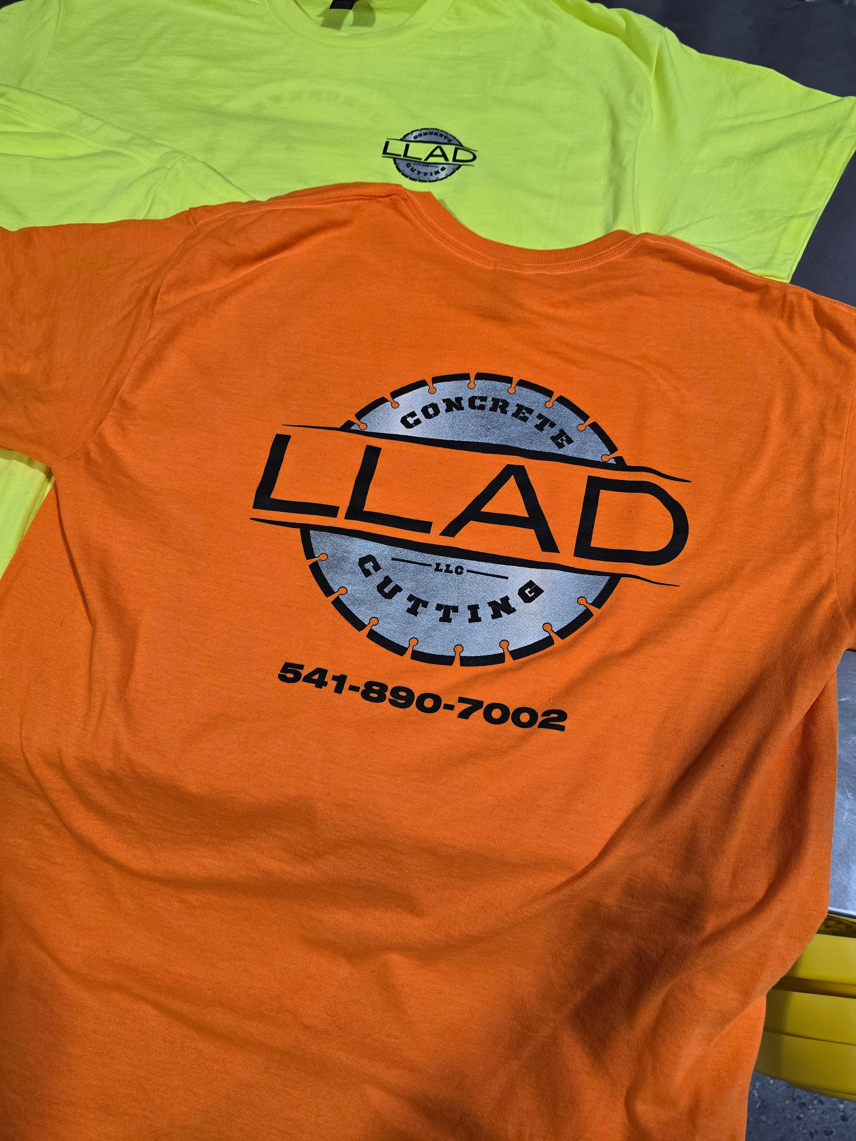 Orange t-shirt with a screen printed logo and text on a green surface