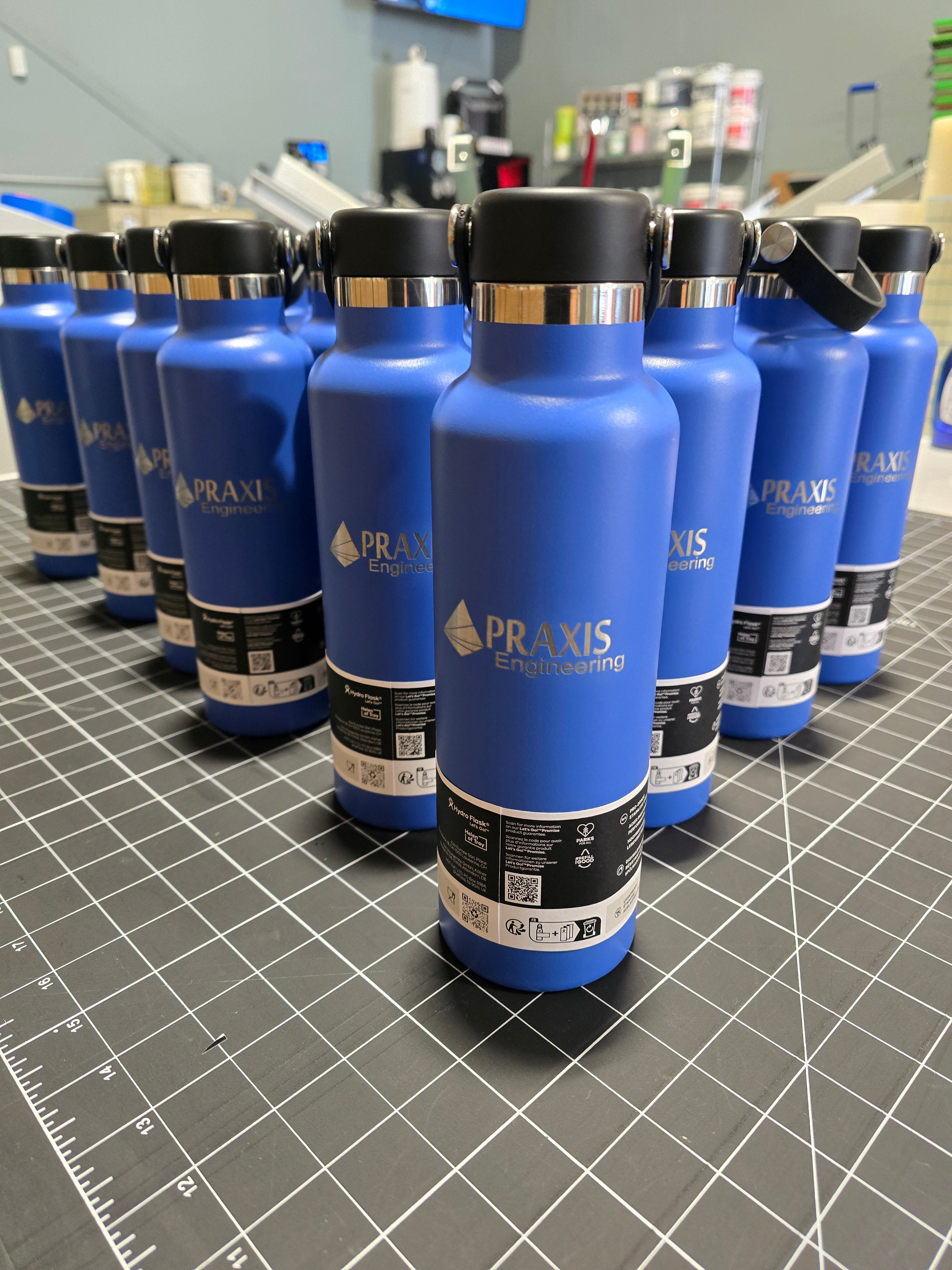 Row of blue Praxis water bottles on a gray surface with a grid pattern